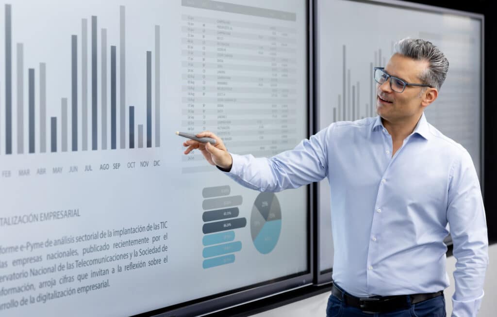 Man in glasses presenting procurement strategy consulting data with bar and pie charts.