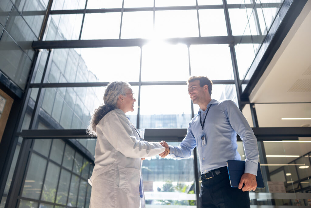 Sales representative greets potential client with a handshake representing telecom b2b growth strategy consulting