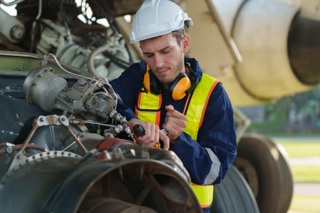 A mechanic in safety gear works on an aircraft engine to ensure fleet readiness.