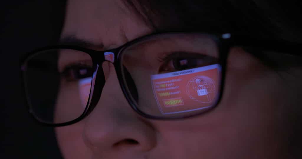 A computer screen with a Healthcare Cyber Resilience warning reflects in a person's glasses.
