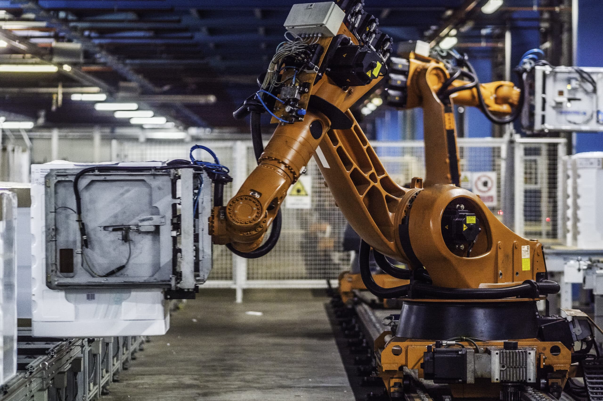 Orange robotic arm assembling appliances, showcasing appliance consulting expertise in action.