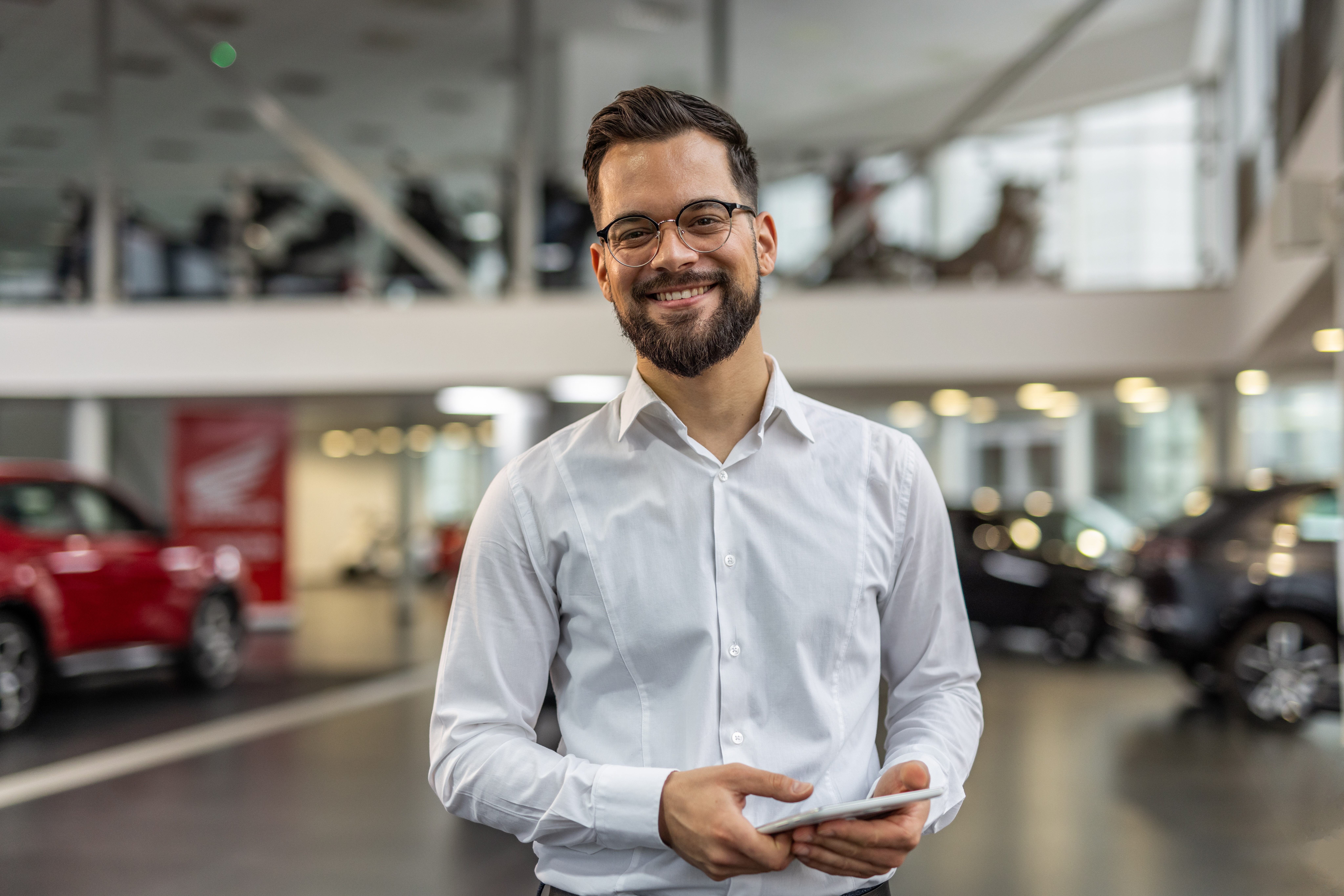 Man in modern car showroom with cars in the background representing automotive retail consulting