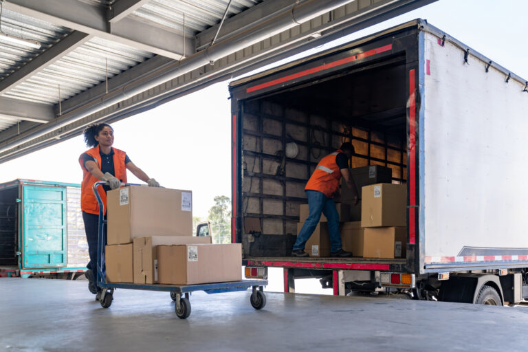 Team of warehouse workers loading boxes for delivery on a truck representing automotive supply chain consulting