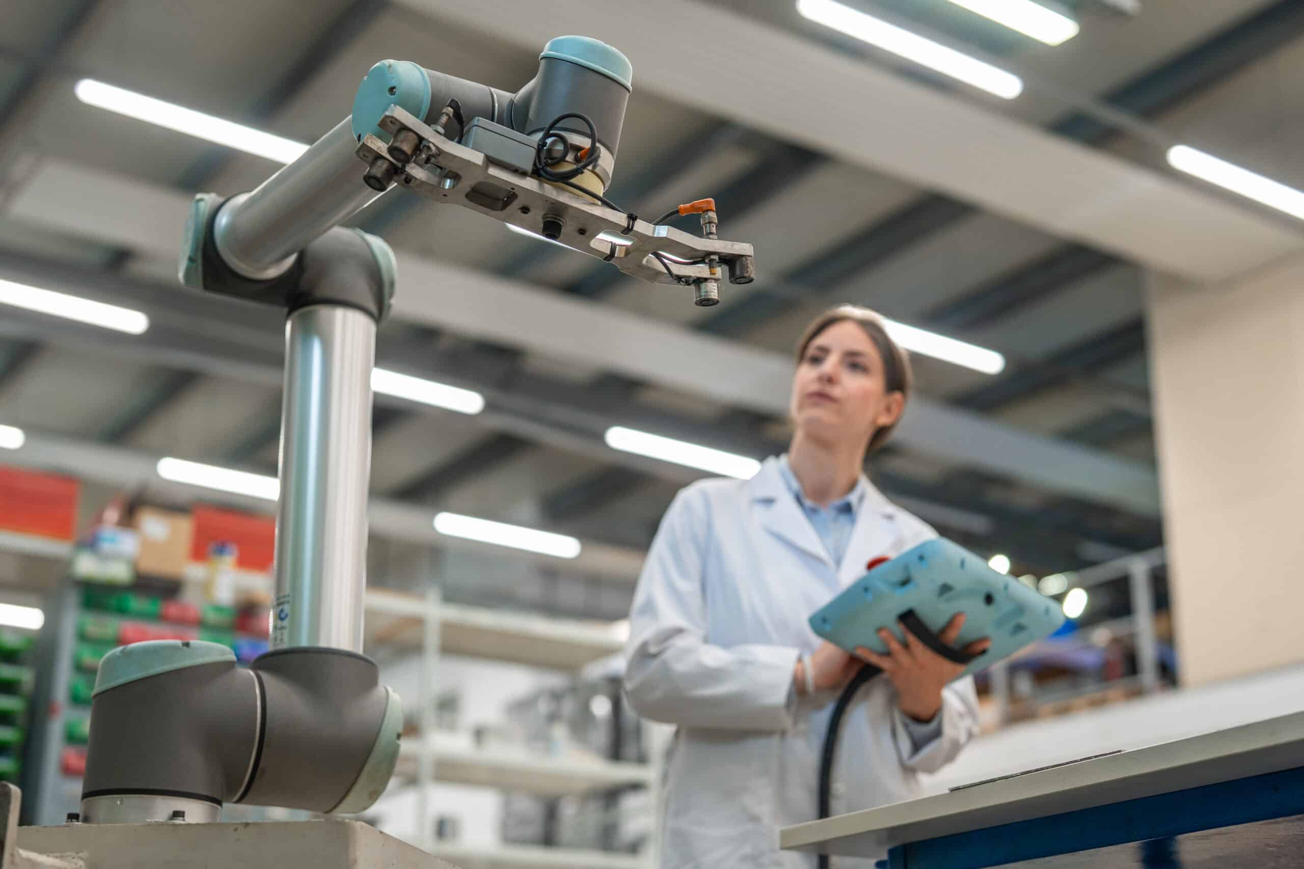 A person in a lab coat operates a robotic arm, showcasing industry 4.0 consulting expertise.