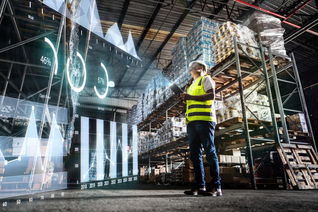 Worker in warehouse checking data on a tablet, guided by Inventory Optimization Consulting.
