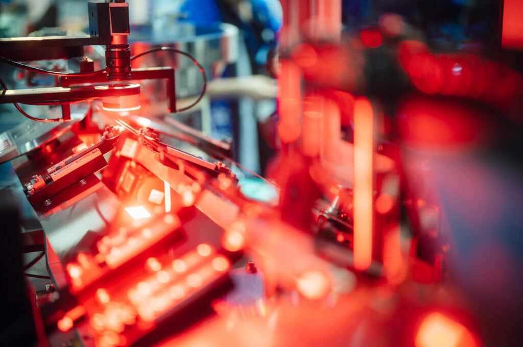 Red lights shine on automated machinery, highlighting Manufacturing Process Consulting expertise.