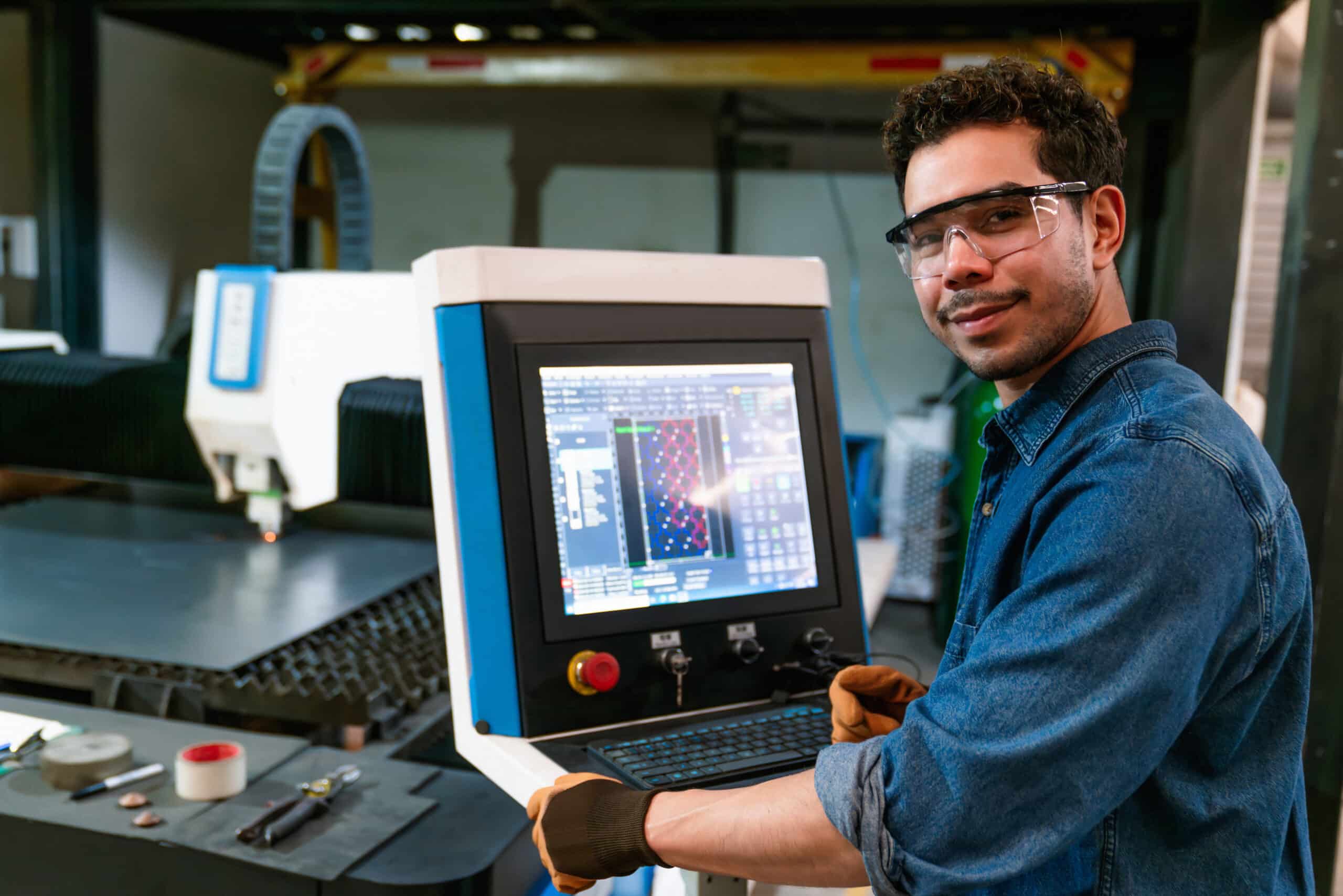 Man wearing safety gear operating a CNC machine in a factory with ot consulting support.