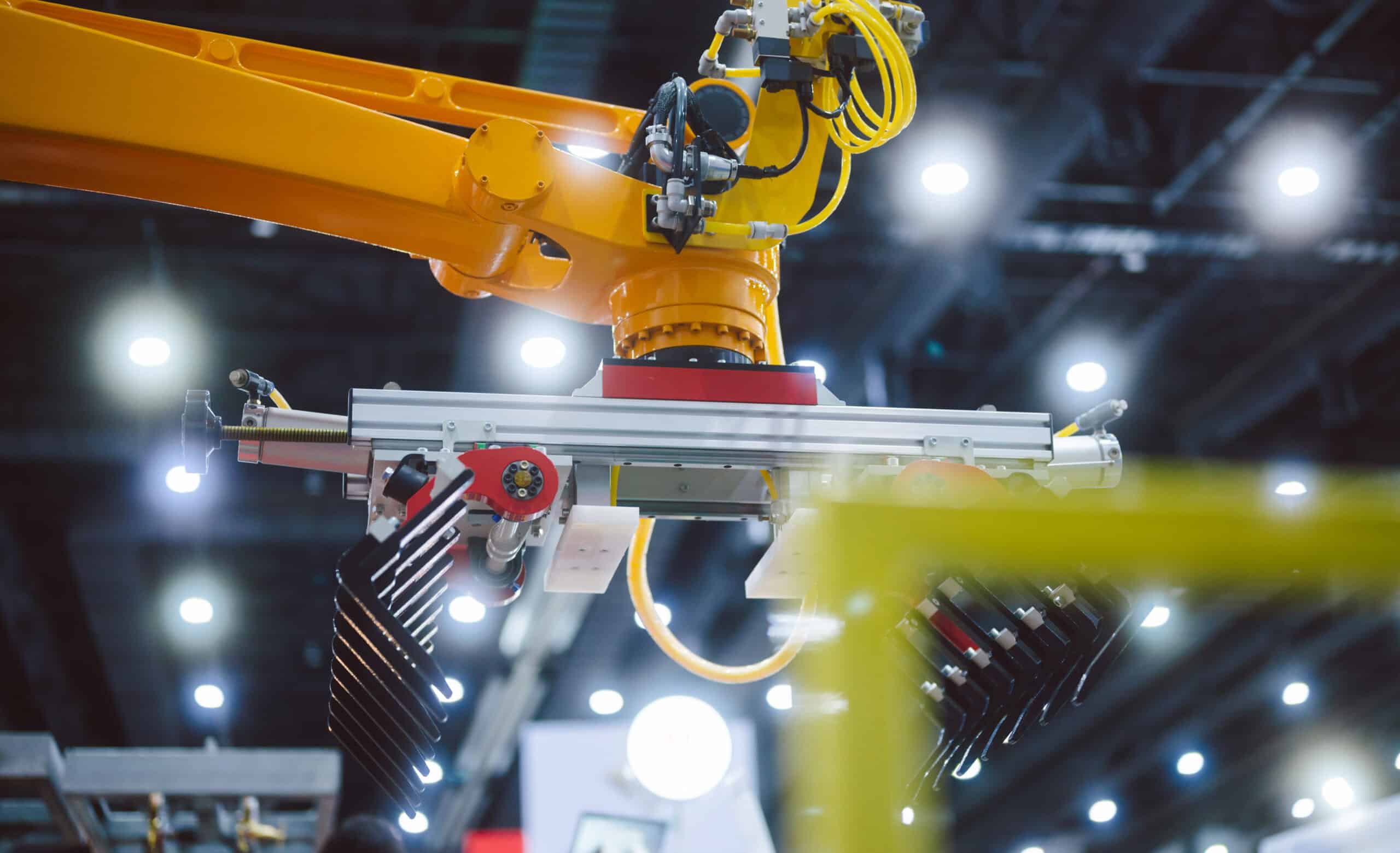 Yellow robotic arm operates in a modern, brightly lit factory with sustainable manufacturing consulting.