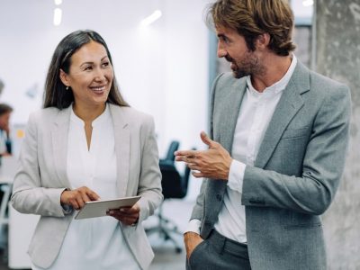 Two professionals in suits discuss workforce development consulting in a modern office.